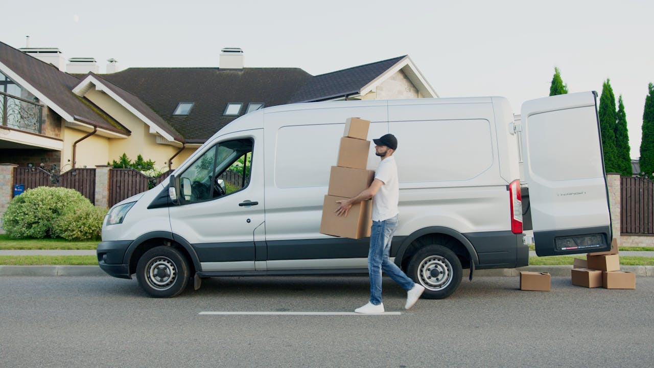 story-01 Man unloading cardboard boxes from a delivery van in a suburban neighborhood street.
